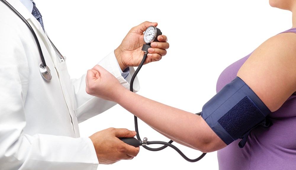 Doctor checking woman's blood pressure